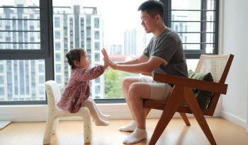 a man sitting in a chair next to a little girl