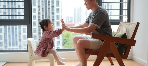 a man sitting in a chair next to a little girl
