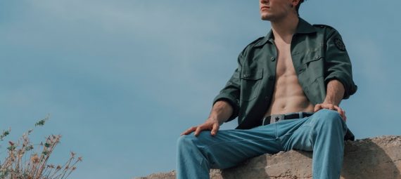 A man sitting on top of a large rock